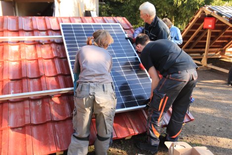 Teilnehmer installieren Solarpaneele an Probedächern